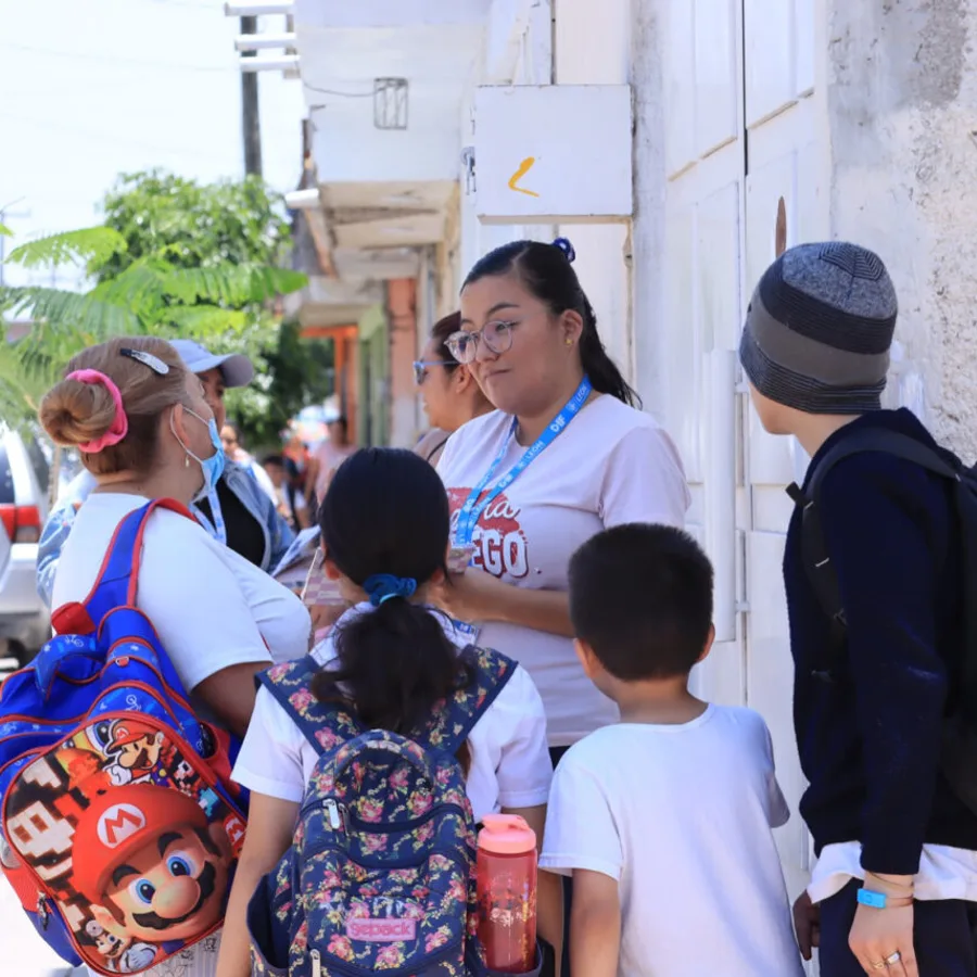 A community health worker talking with parents and schoolchildren on a residential street during safe-streets data collection in León.